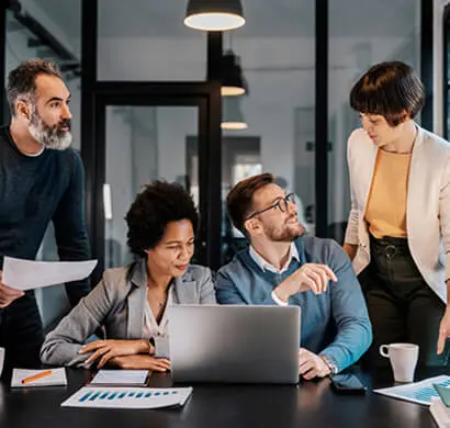 Sesión de trabajo del equipo de PluginX HUB alrededor de una mesa con laptops